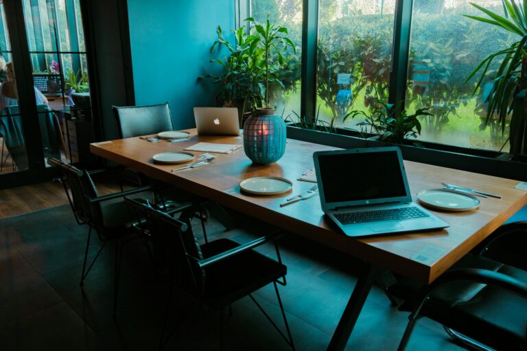 A laptop sits on a table next to a plate of food, indicating a blend of work and meal time.